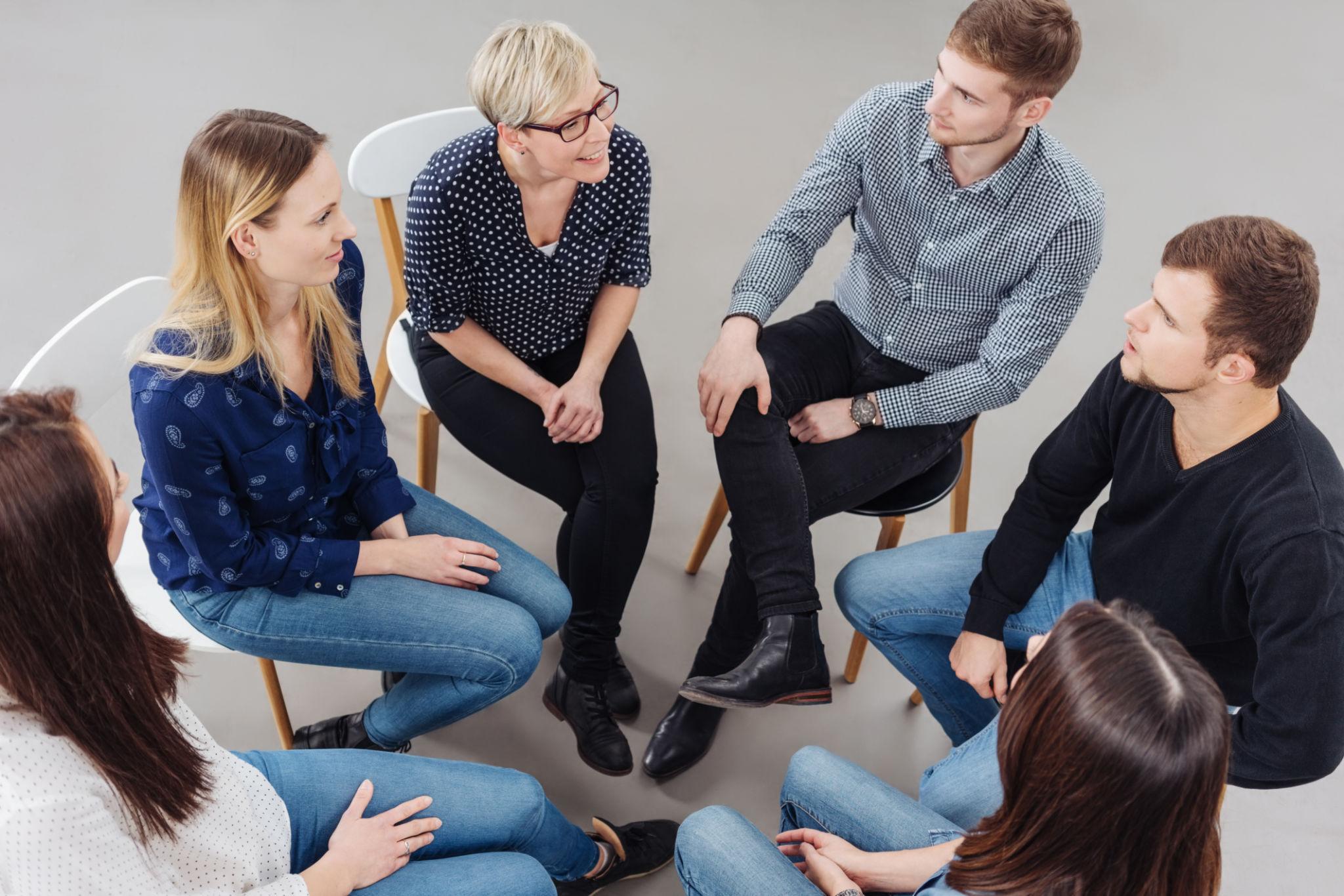 Kleine groep cursisten in gesprek tijdens een Nederlandse conversatieles, in een veilige omgeving waar iedereen de kans krijgt om te spreken.