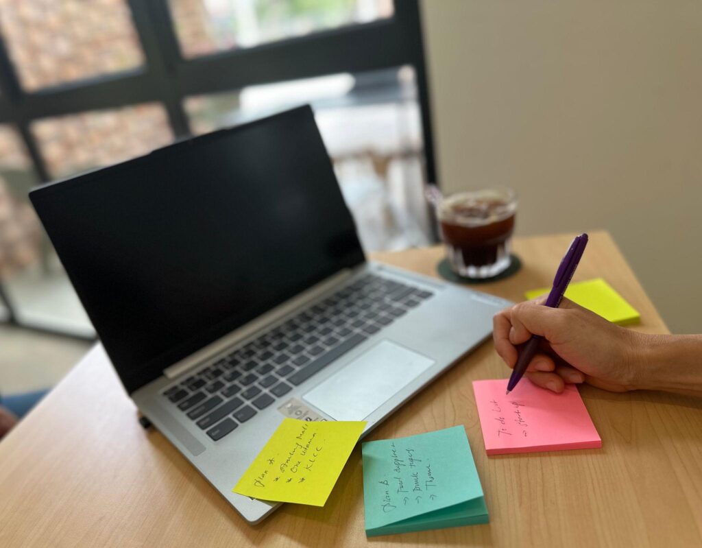 Persoon bereidt zich voor op een gesprek met notities, woordenschat en geheugensteuntjes op Post-its naast een laptop.
